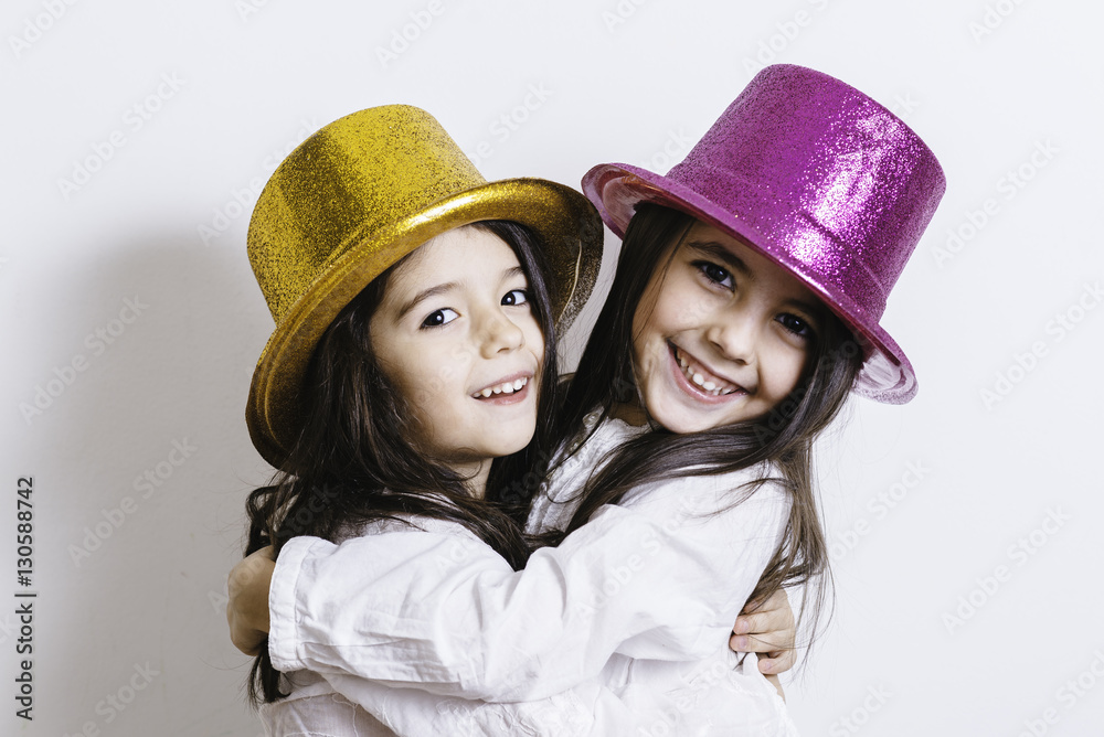 Two girls posing with yellow and pink shiny hats Two girls posing with yellow and pink shiny hats