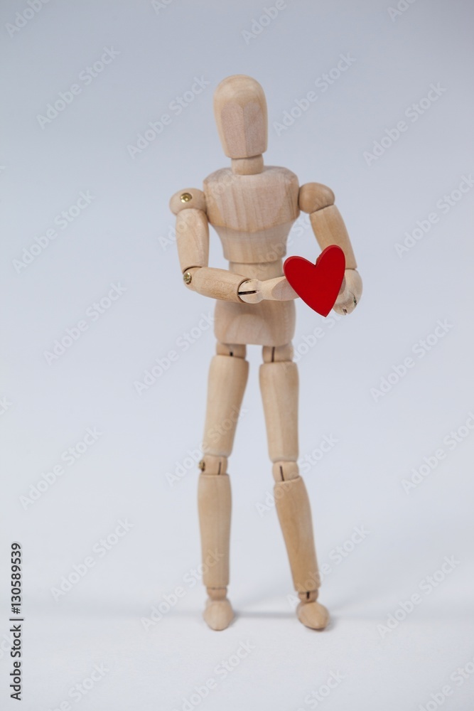 Wooden figurine standing and holding a red heart Wooden figurine standing and holding a red heart