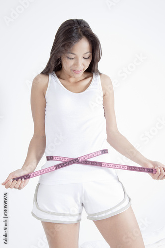 Young woman measuring waist with tape © imagenavi