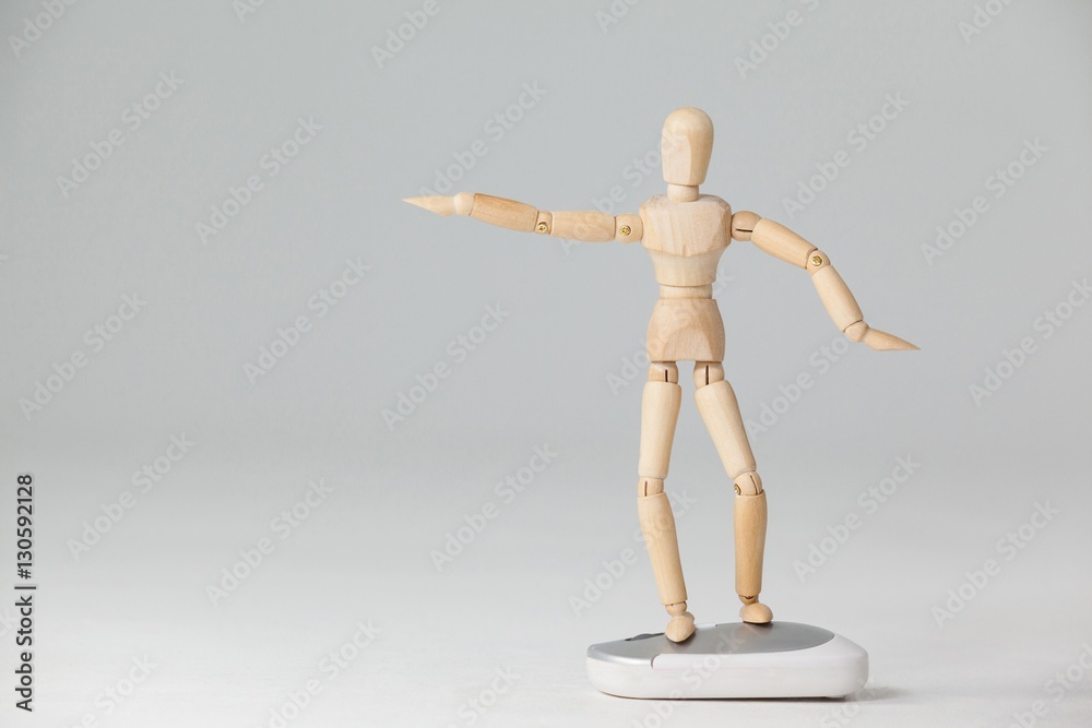 Wooden figurine standing with arms spread on a mouse Wooden figurine standing with arms spread on a mouse