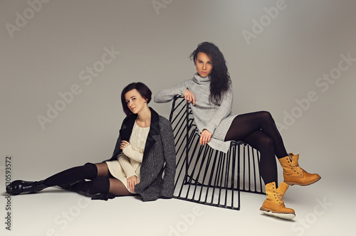 Two attractive brunette women posing in a studio. photo