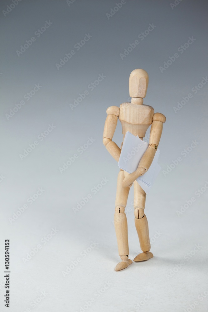 Wooden figurine standing and holding documents Wooden figurine standing and holding documents