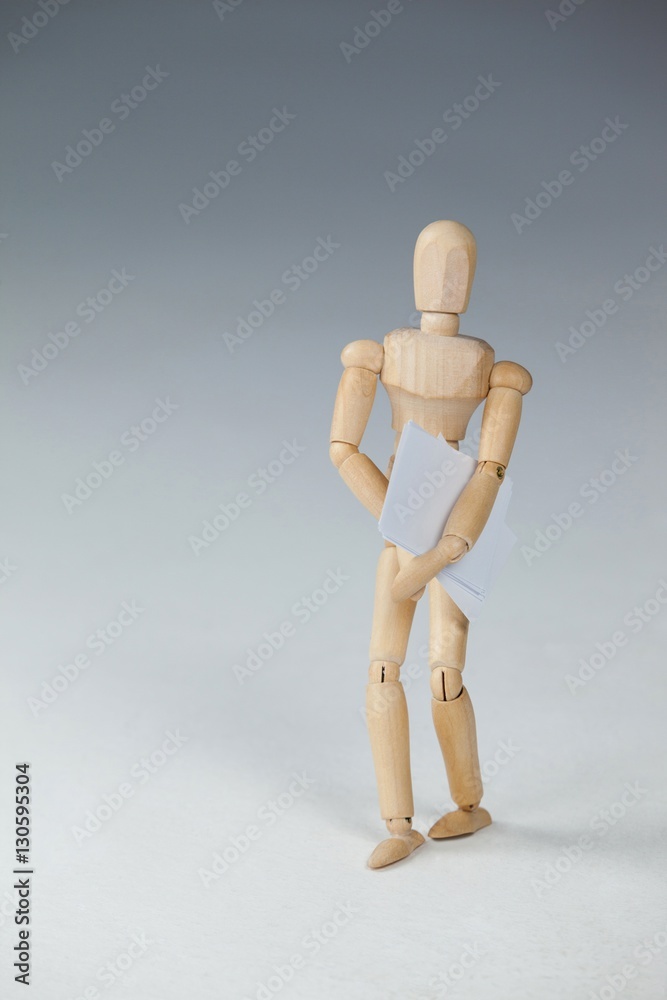 Wooden figurine standing and holding documents Wooden figurine standing and holding documents