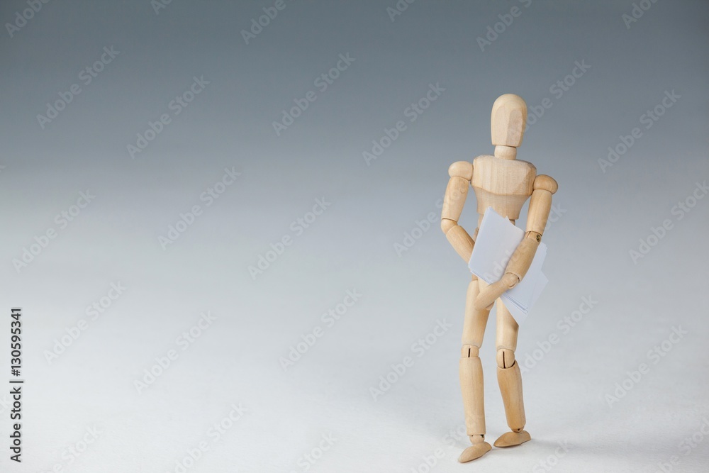 Wooden figurine standing and holding documents Wooden figurine standing and holding documents