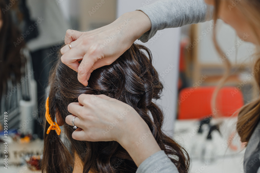 Stylist curling hair and making wedding hairstyle for brown haired woman. Stylist curling hair and making wedding hairstyle for brown haired woman.