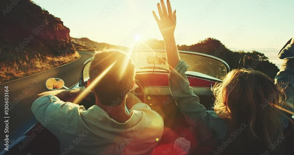 Happy couple driving on country road into the sunset in classic vintage ...