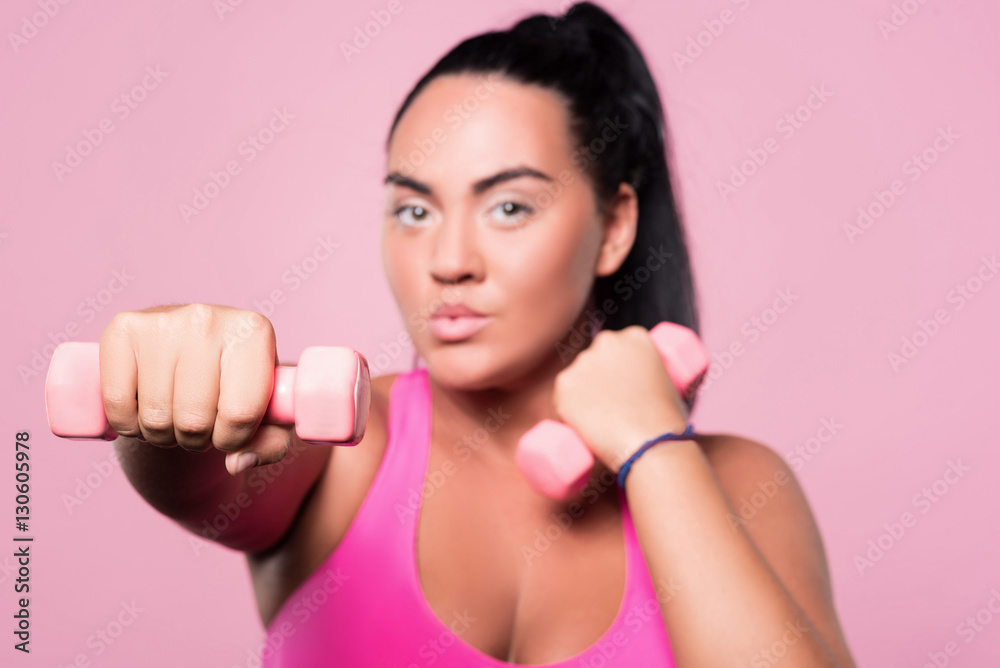 Close up of chubby woman doing boxing exercises with dumbbells Close up of chubby woman doing boxing exercises with dumbbells