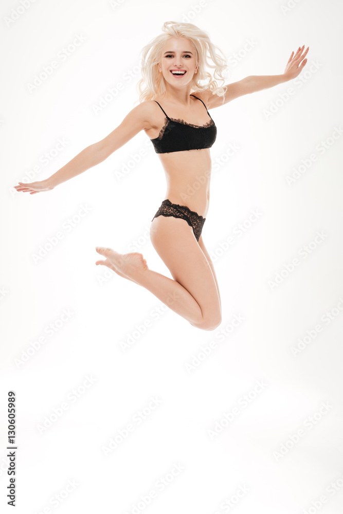 Portrait of a happy blonde woman in black linngerie jumping Portrait of a happy blonde woman in black linngerie jumping