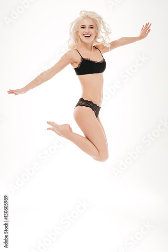 Portrait of a happy blonde woman in black linngerie jumping