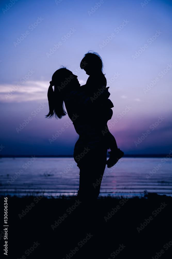 Silhouette side view of mother and child enjoying at riverside.