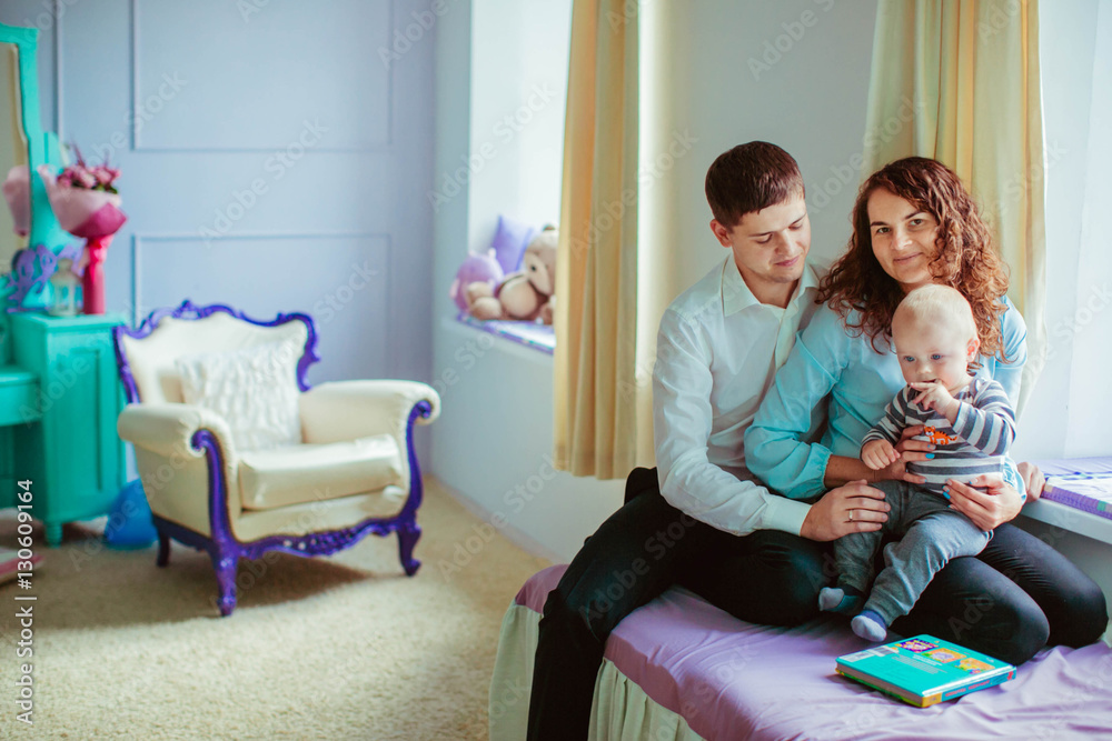 happy and young parents with their cute son sitting on the windo happy and young parents with their cute son sitting on the windo