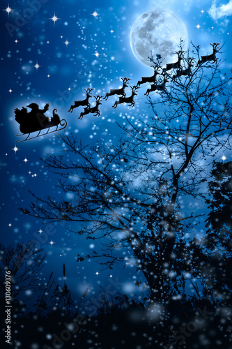 Fototapeta Naklejka Na Ścianę i Meble -  Christmas background. Silhouette of Santa Claus flying on a sleigh pulled by reindeer. 
