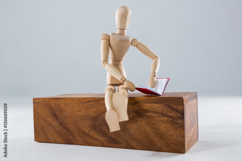Figurine sitting on a wooden sofa table and reading a book Figurine sitting on a wooden sofa table and reading a book