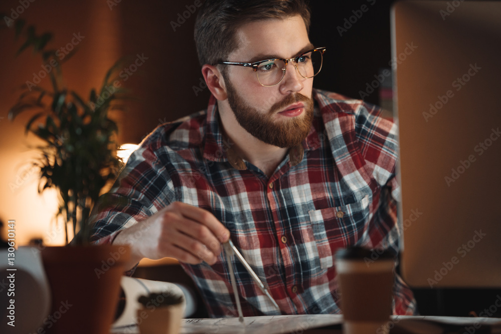 Bearded designer working late at night and looking on computer. Bearded designer working late at night and looking on computer.