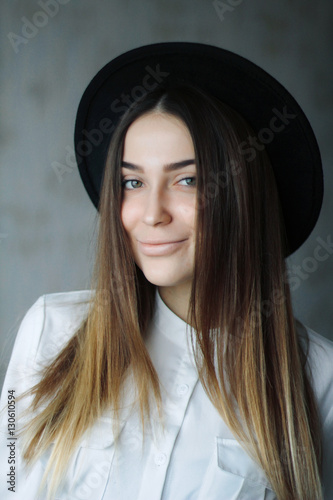 portrait of a girl brunette in black hat and white shirt. She is smiling cute © zvkate