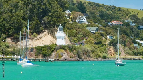 Akaroa New Zealand Harbour Waterfront Residential Properties against the Hills with a Lighthouse during the Summertime photo