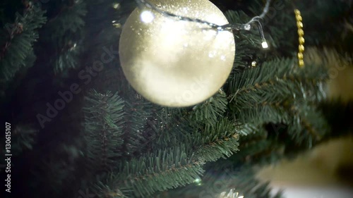 Slider view of big golden matte ball and lights. New Year's and abstract blurred shopping mall background with Christmas tree decorations. photo