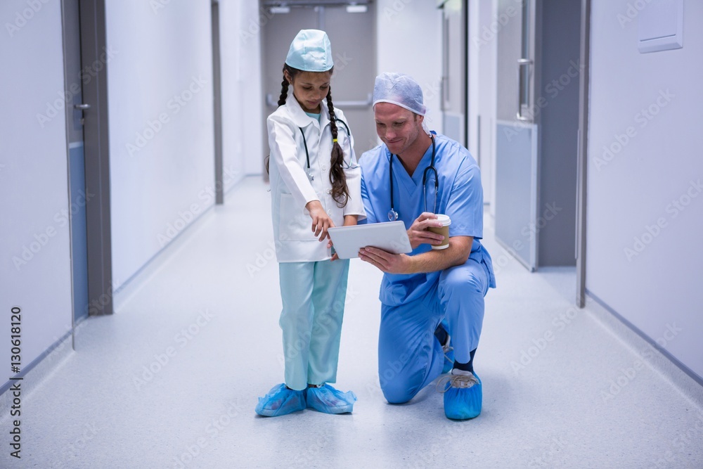 Smiling doctor and girl using digital tablet in corridor Smiling doctor and girl using digital tablet in corridor