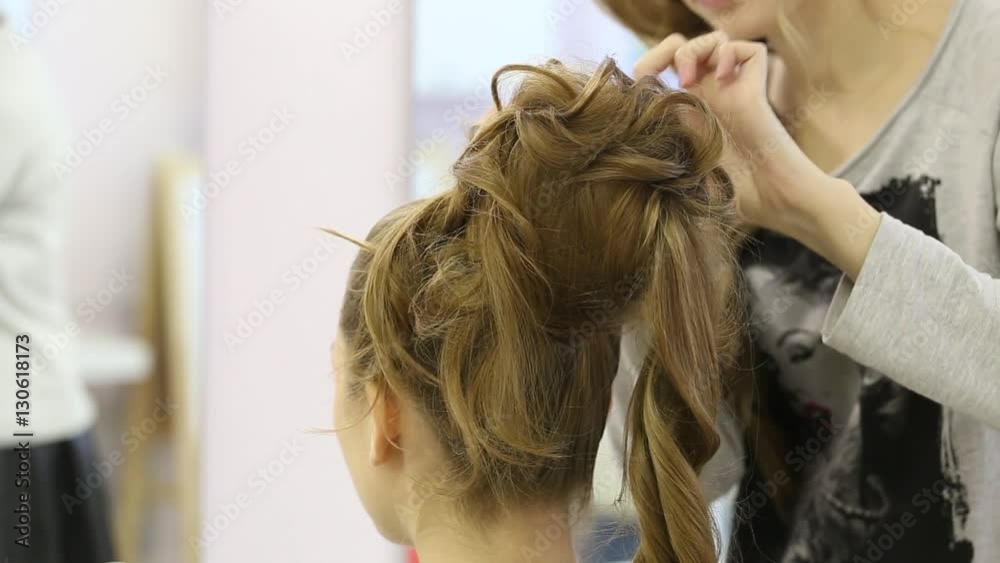 Professional hairdresser doing hairstyle with bun and curls for beautiful healthy hair Professional hairdresser doing hairstyle with bun and curls for beautiful healthy hair