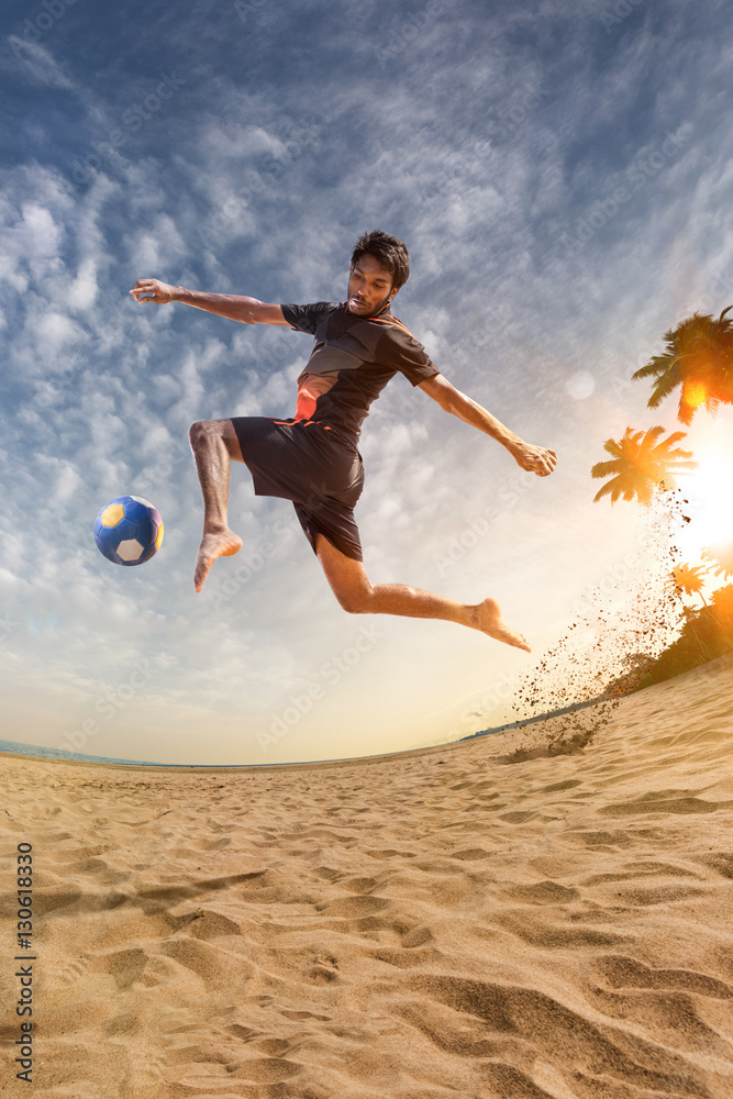 Beach soccer player in action. Sunny beach wide angle and sea Beach soccer player in action. Sunny beach wide angle and sea