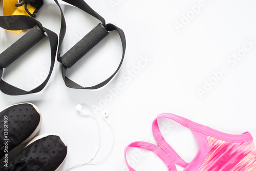 Flat lay of earphone, red dumbbells and sport equipment on white