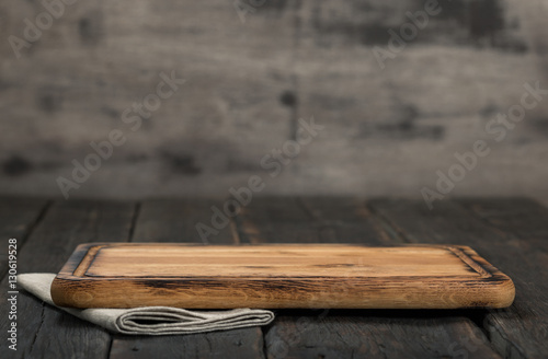 Chopping board on dark wooden background close up