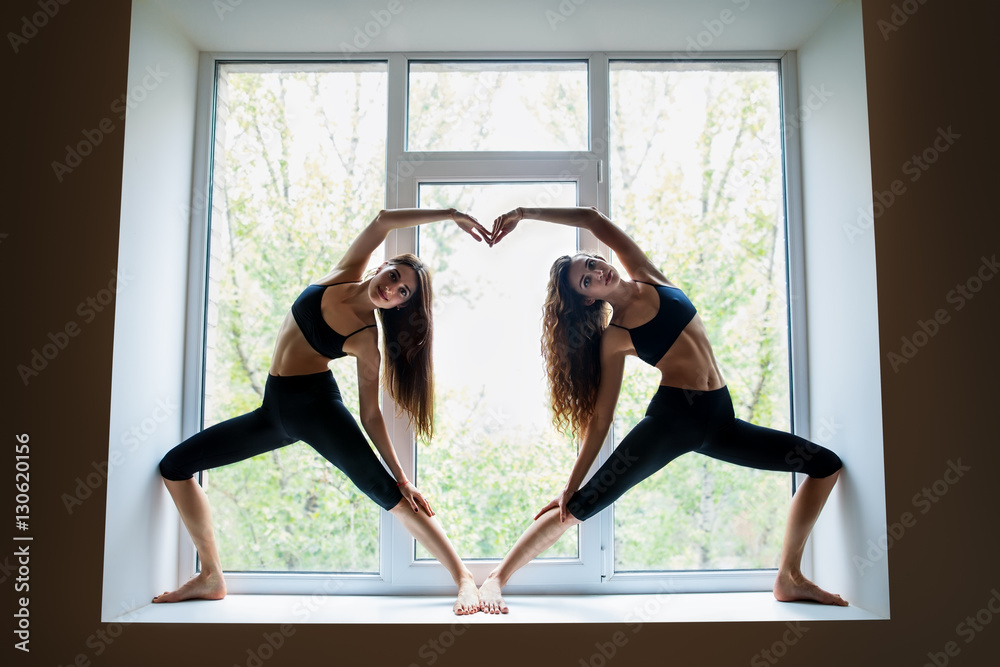Εκτύπωση καμβά Two beautiful women doing yoga asana showing heart symbol on win
