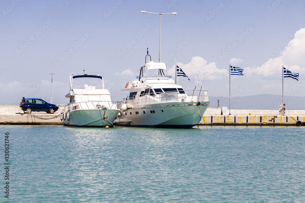 two boats at the pier on the background of the Greek flag, the Ionian Sea