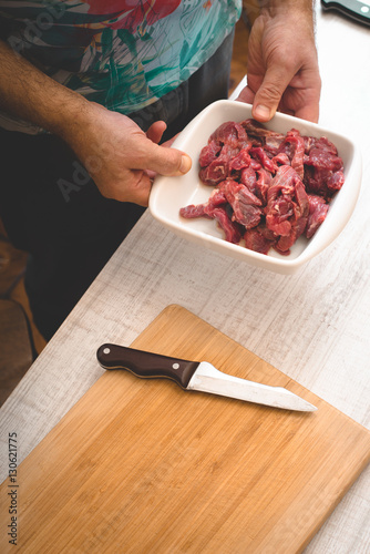 Man hold the plate with raw sliced meat