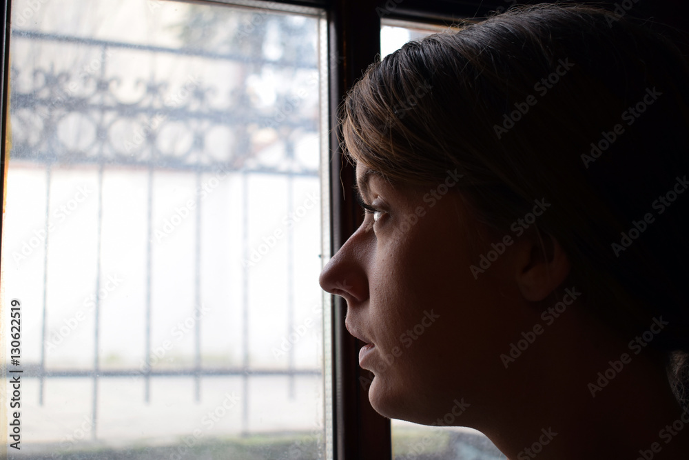 Young depressed girl is thinking and looking out the window.She is sad. Young depressed girl is thinking and looking out the window.She is sad.