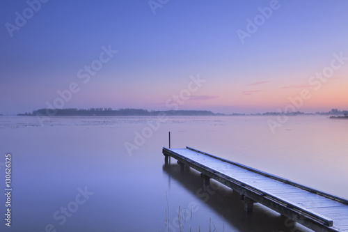 Jetty on a still lake in winter in The Netherlands