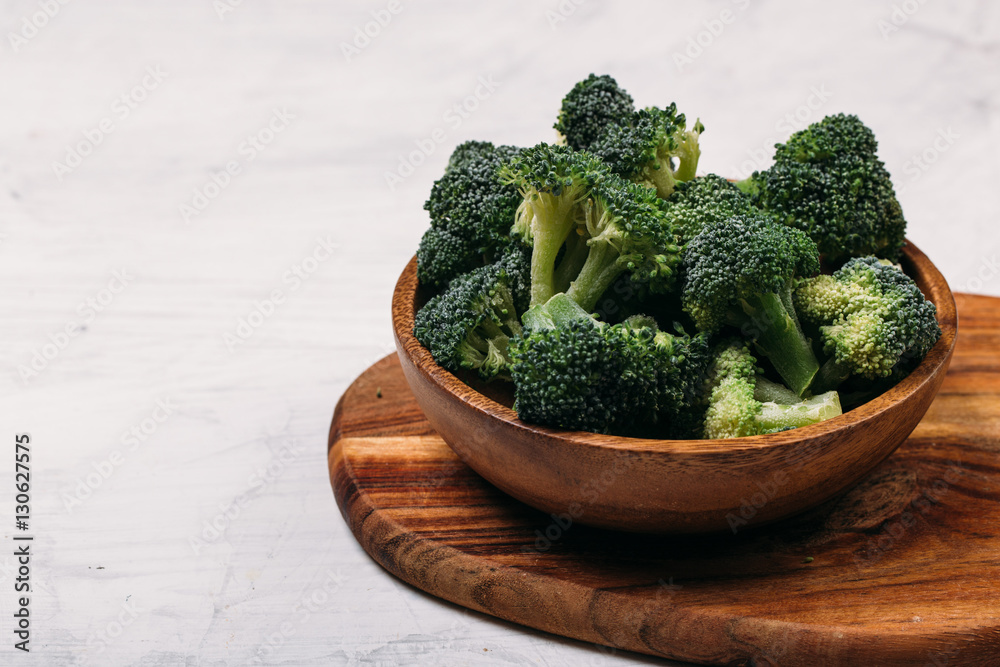 Green broccoli in wooden plate on white background Green broccoli in wooden plate on white background