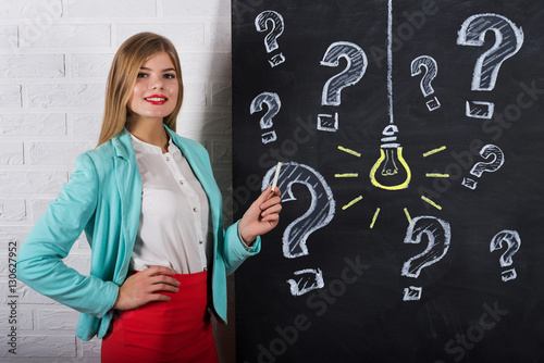 An attractive young woman with chalk at the blackboard with Idea Bulb Concept photo