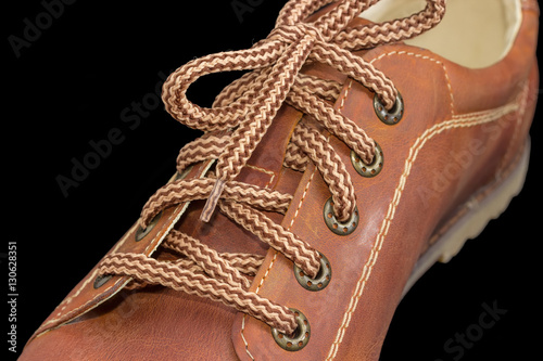 Fragment of brown mens shoe with shoelaces on dark background