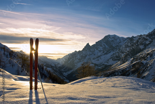 tra i due sci,si vede il tramonto del sole dietro le montagne del monte Bianco
