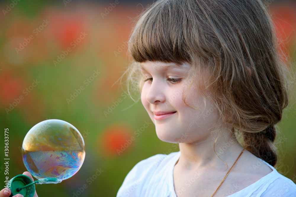 A little girl blowing soap bubbles in summer park A little girl blowing soap bubbles in summer park