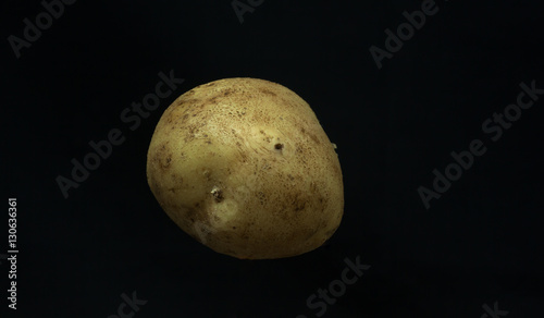 Potato on black background, floating on air.