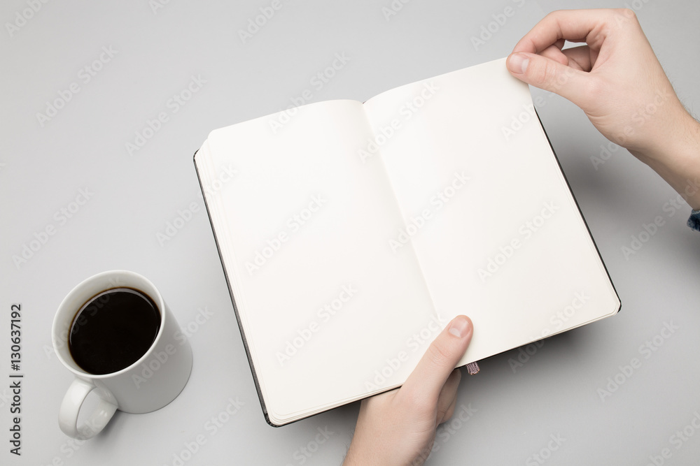 Obraz premium Hand is holding the notebook and coffee cup