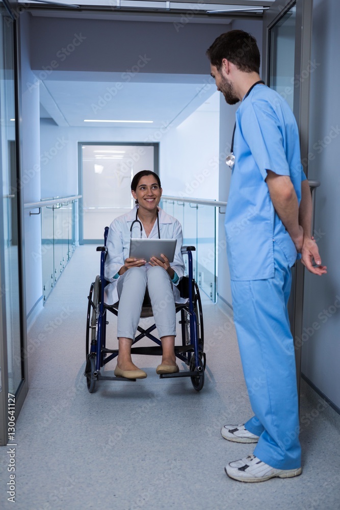 Female doctor sitting on wheelchair and interacting Female doctor sitting on wheelchair and interacting