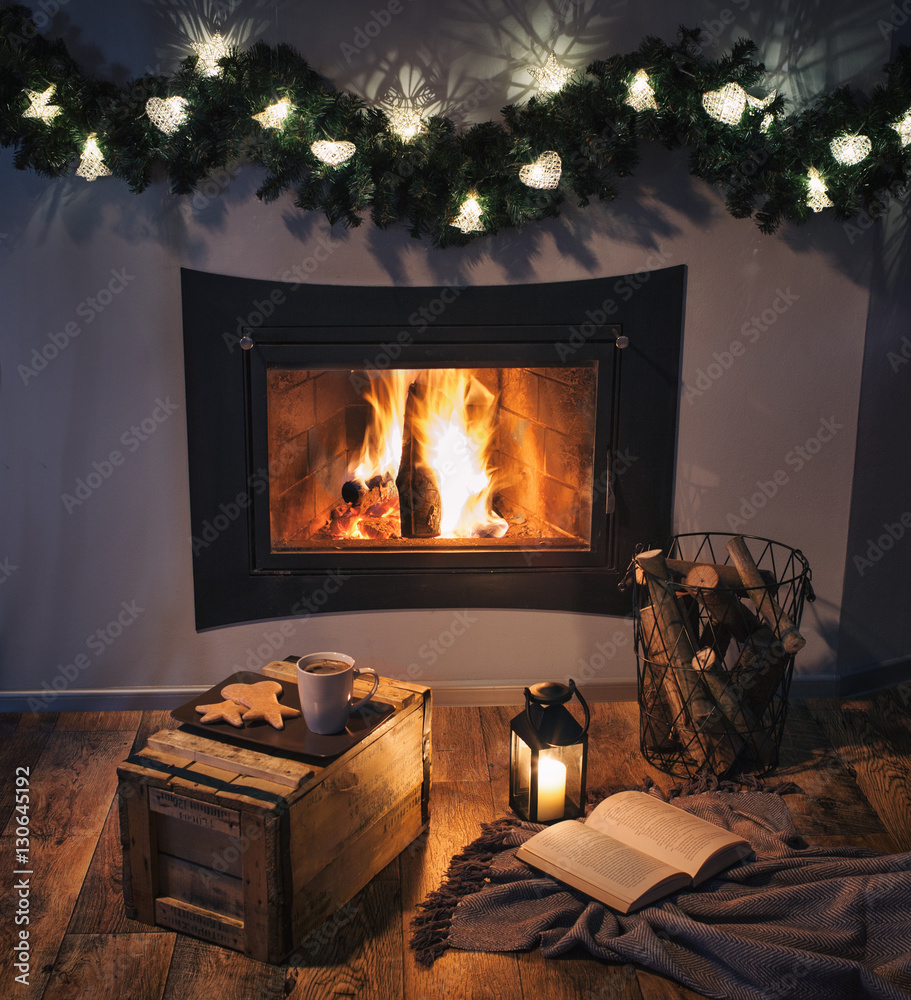 Lights decorated fireplace, lantern, coffee, sweets and a book