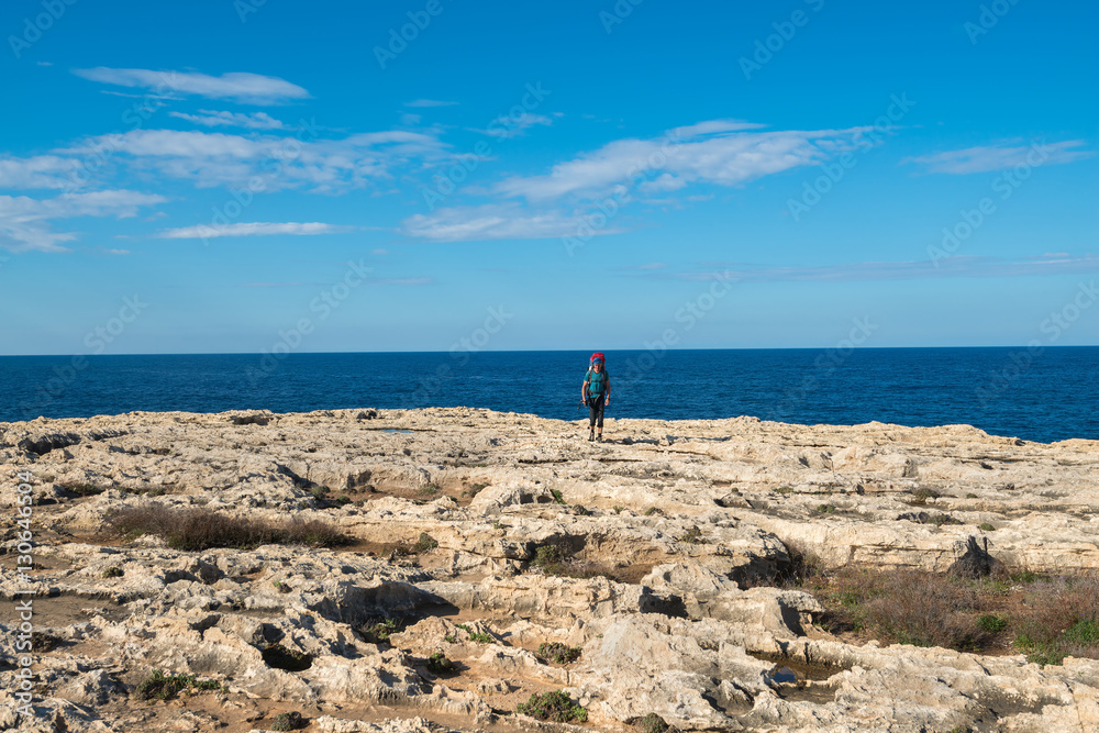 Hiker goes along rocky coast of sea Hiker goes along rocky coast of sea
