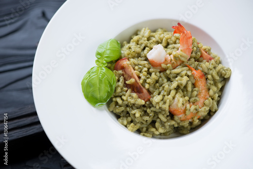 Close-up of a white plate with spinach and tiger shrimps risotto