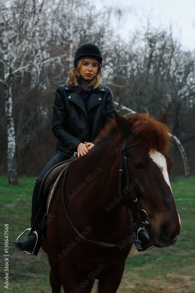 Beautiful young rider sitting on a horse in the forest Beautiful young rider sitting on a horse in the forest