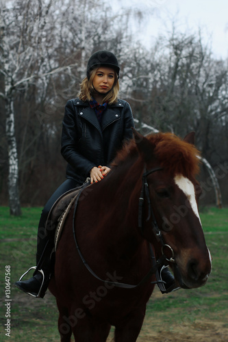 Beautiful young rider sitting on a horse in the forest