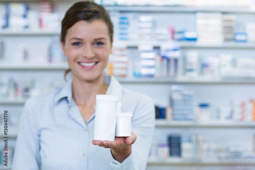 Smiling pharmacist showing medicine container in pharmacy Smiling pharmacist showing medicine container in pharmacy