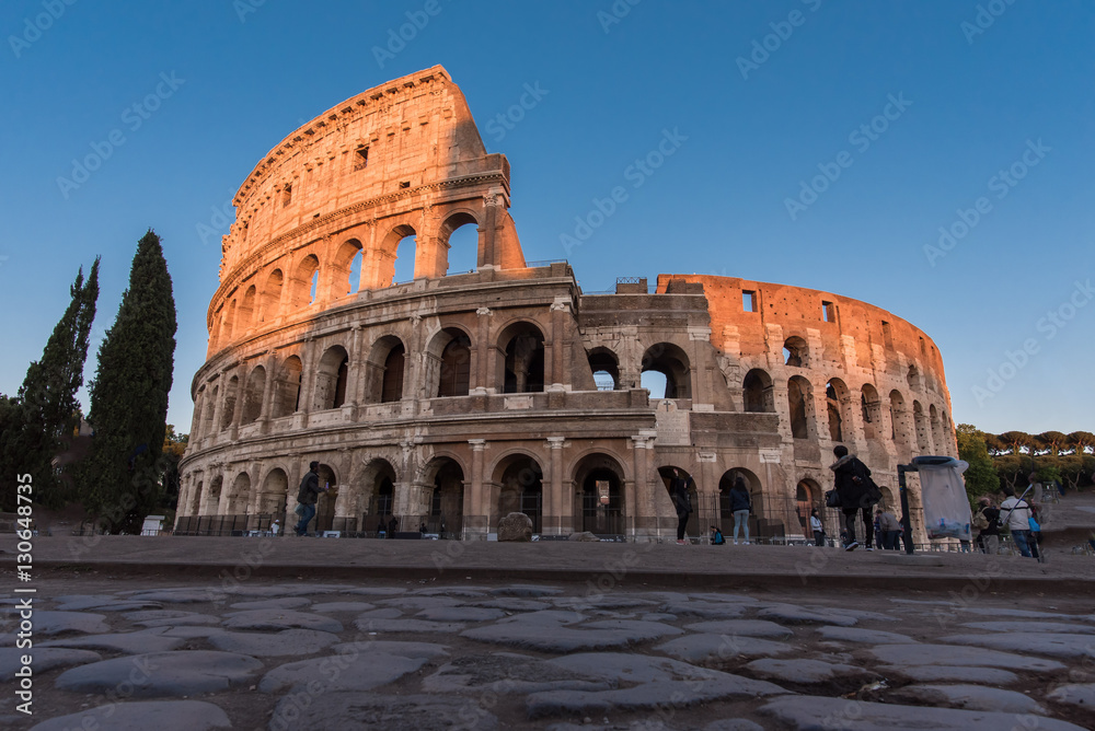 Roman coliseum at sunset with top lit up by evening sun