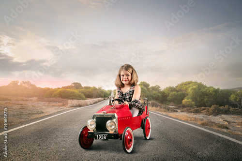 Child in a red toy car