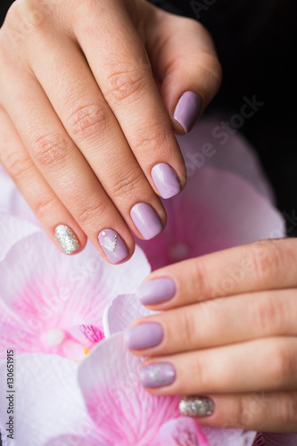 Hand with manicured nails on a pink background flowers