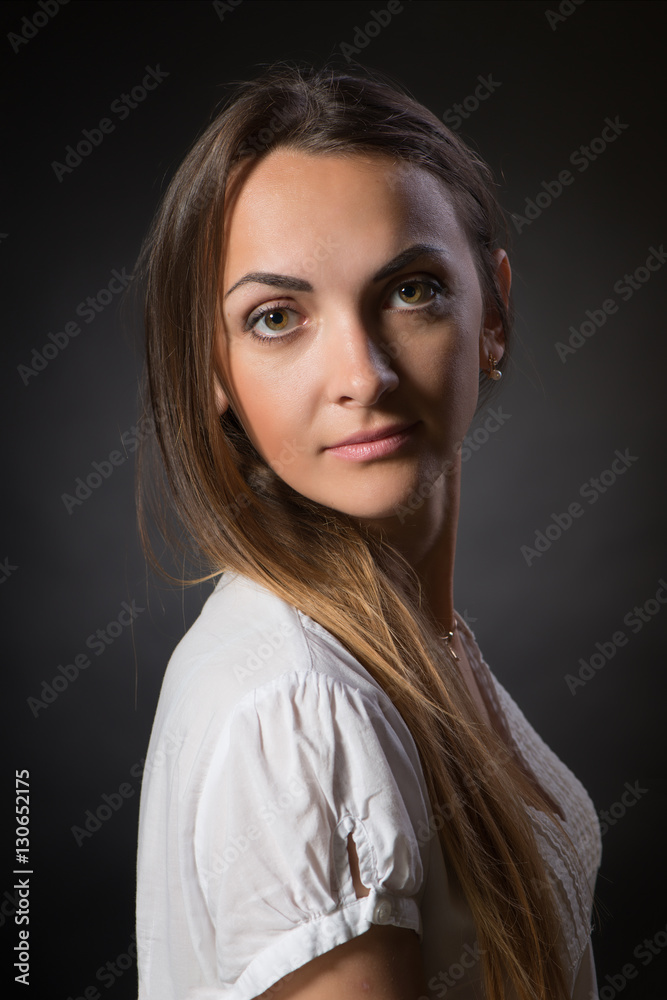 The young woman with long hair in a white jacket against  dark background