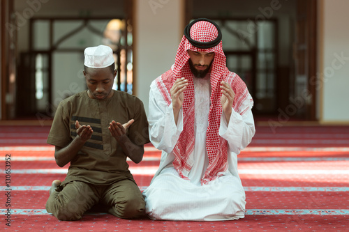 Two religious muslim man praying together inside the mosque